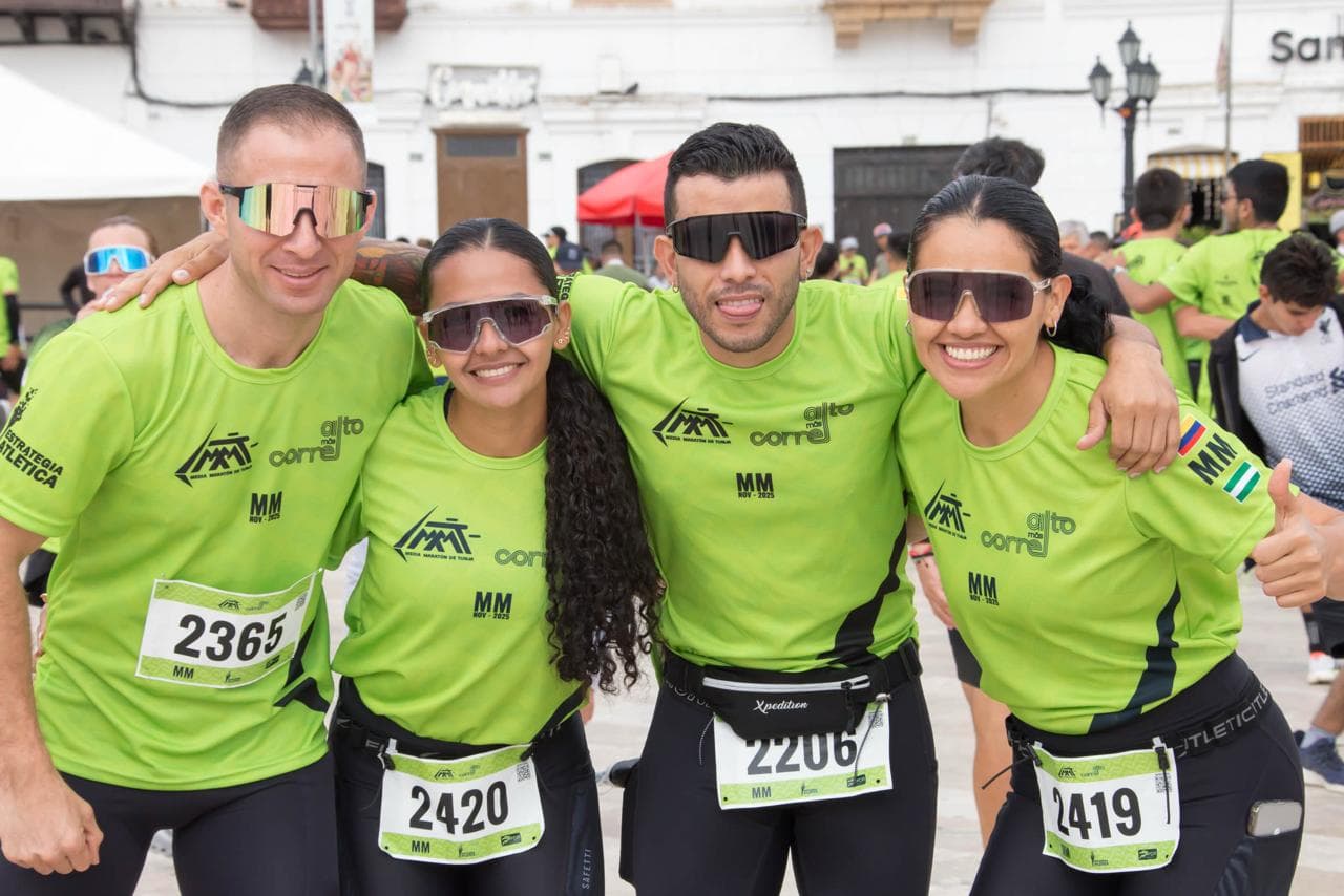 Grupo de cuatro corredores posando con su dorsal