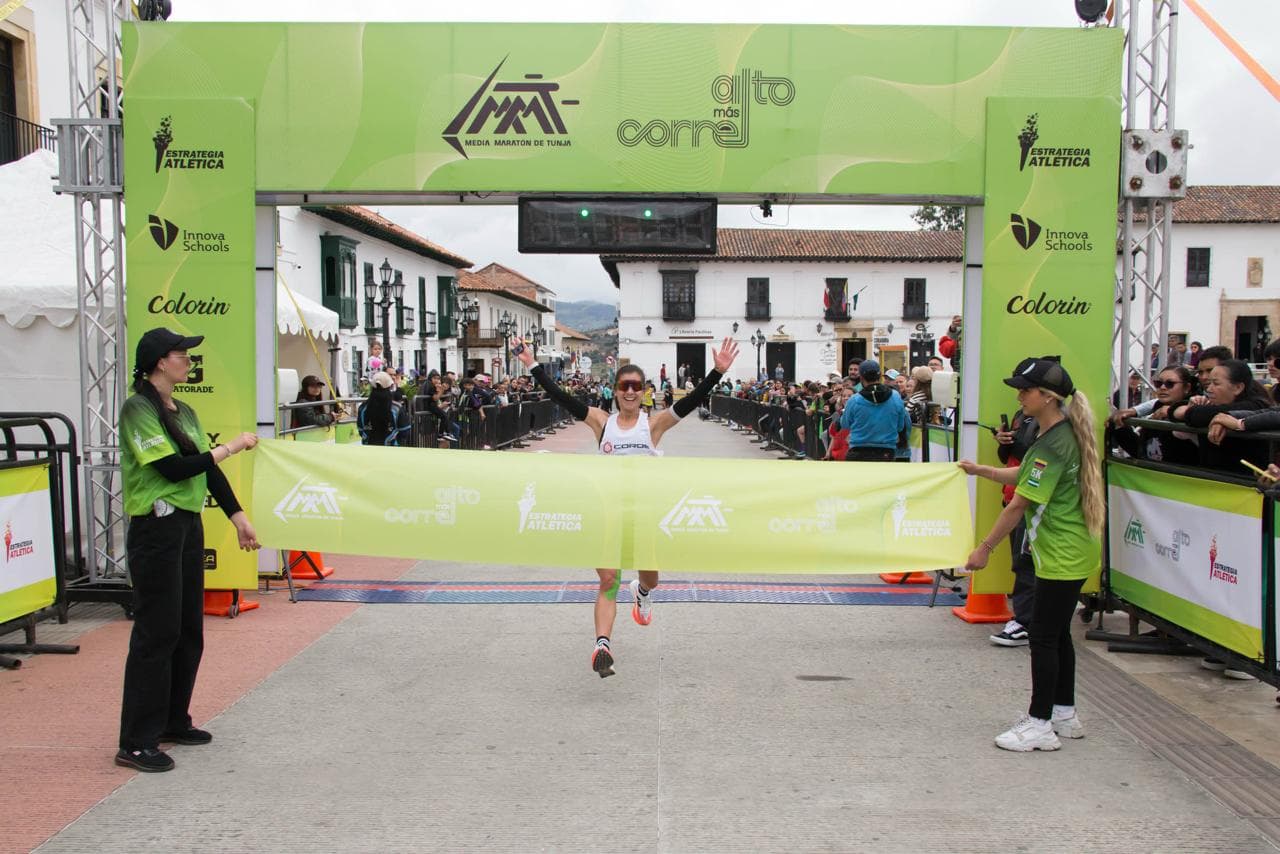 Corredora cruzando la meta bajo el arco de llegada